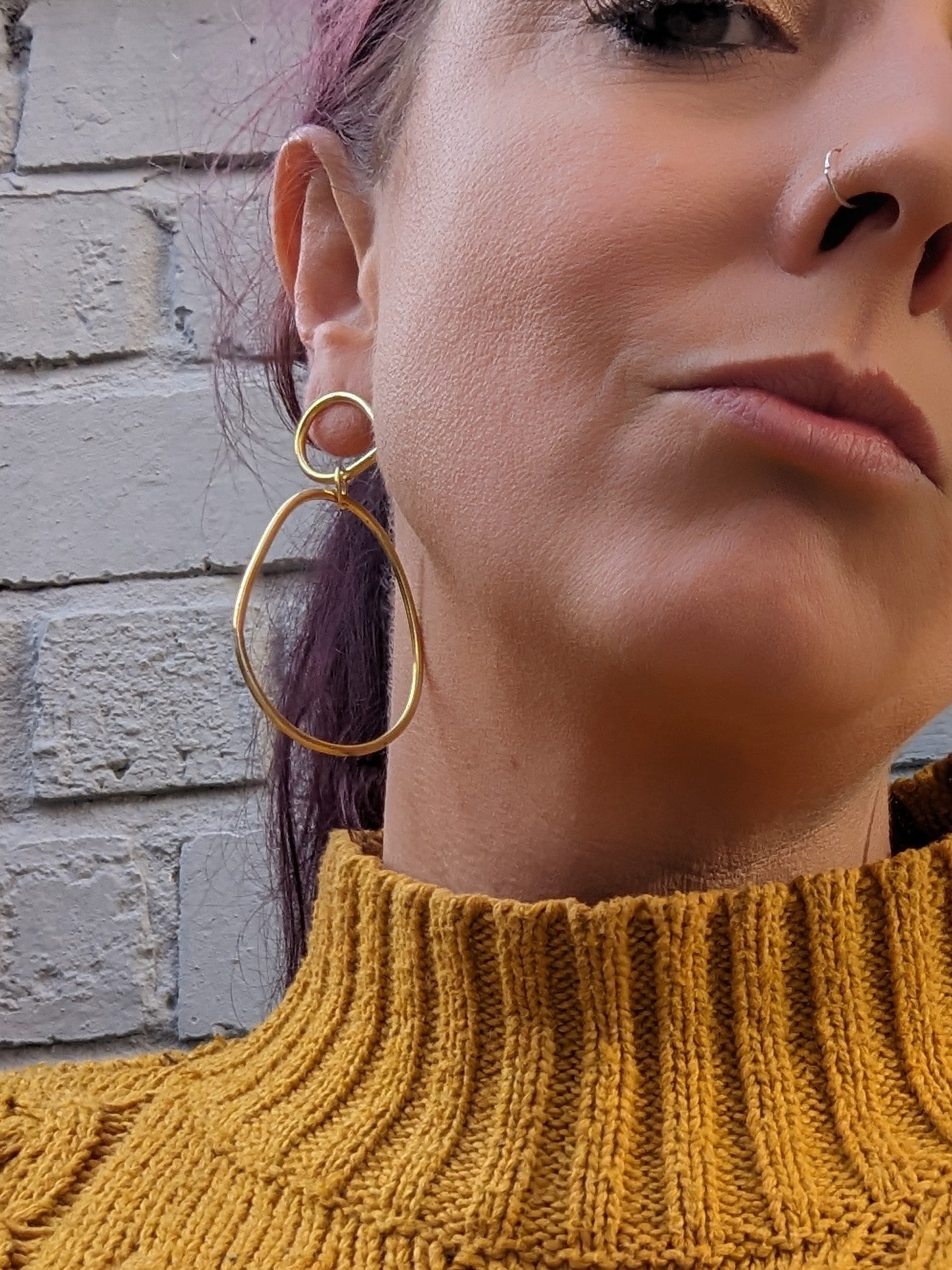 Model adorning large gold statement earrings