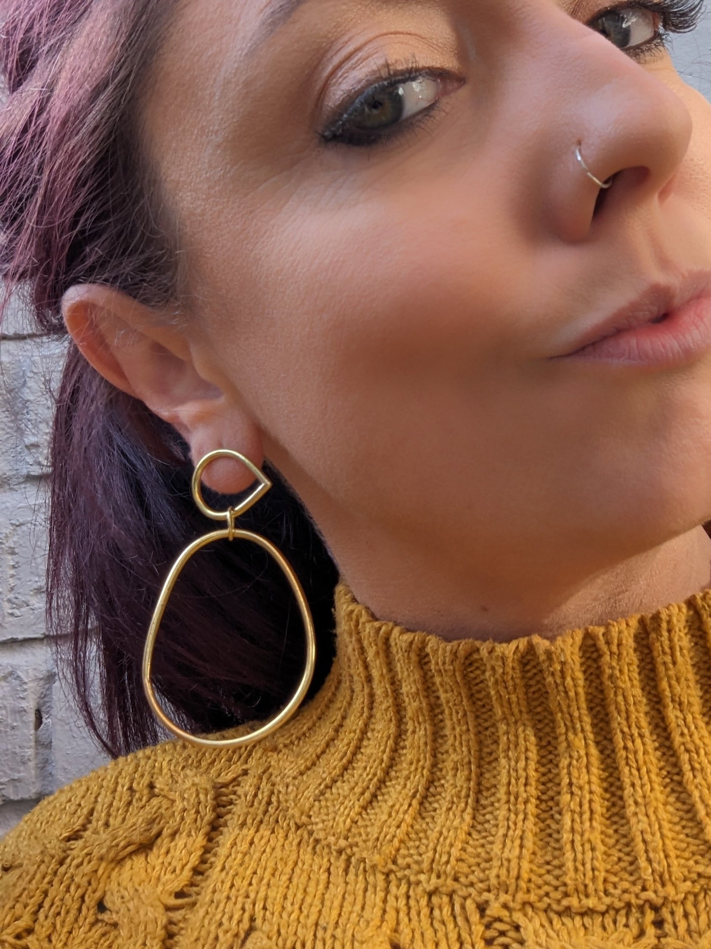 Model adorning large gold statement earrings