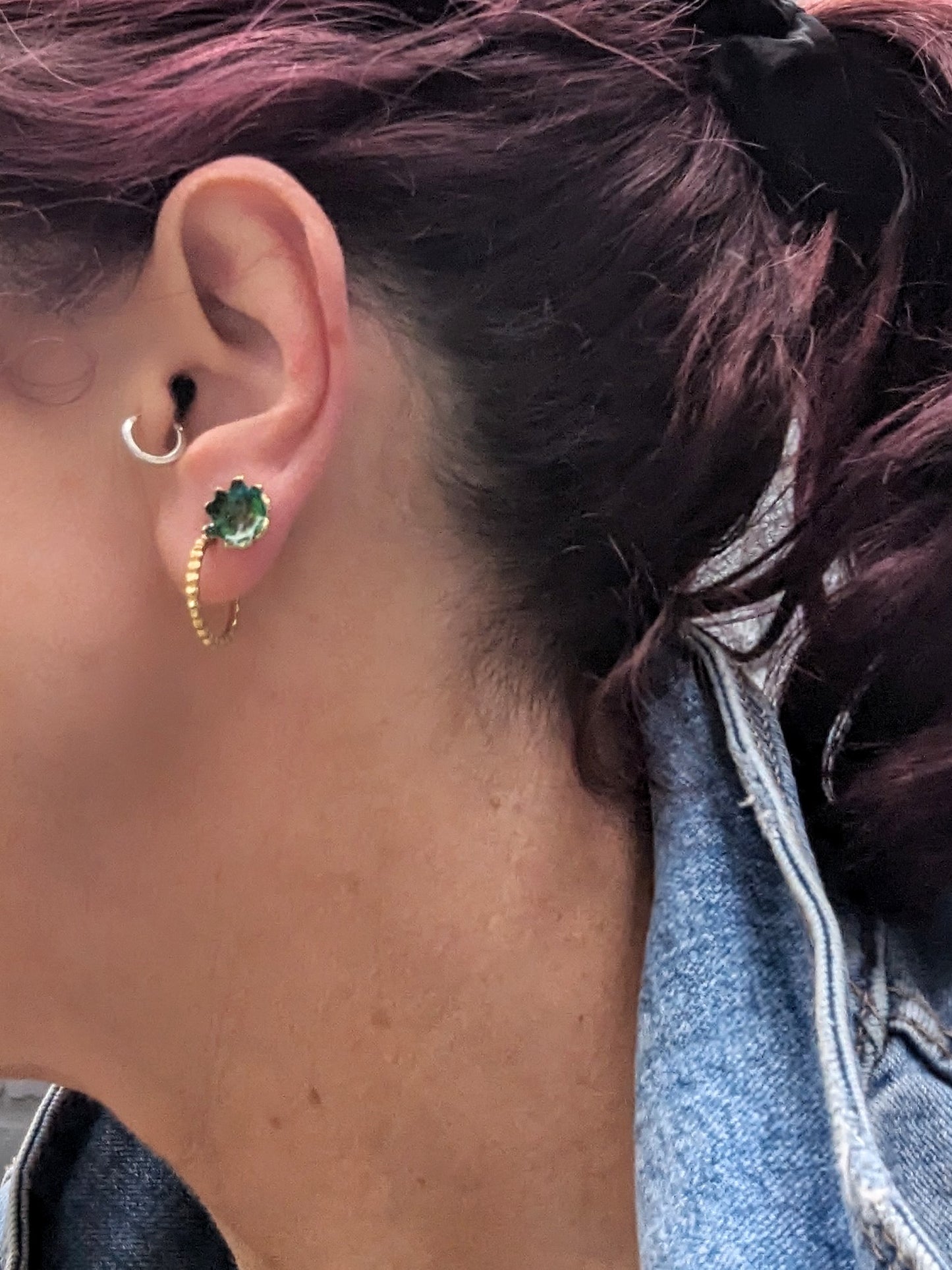 Model wearing green stud earrings