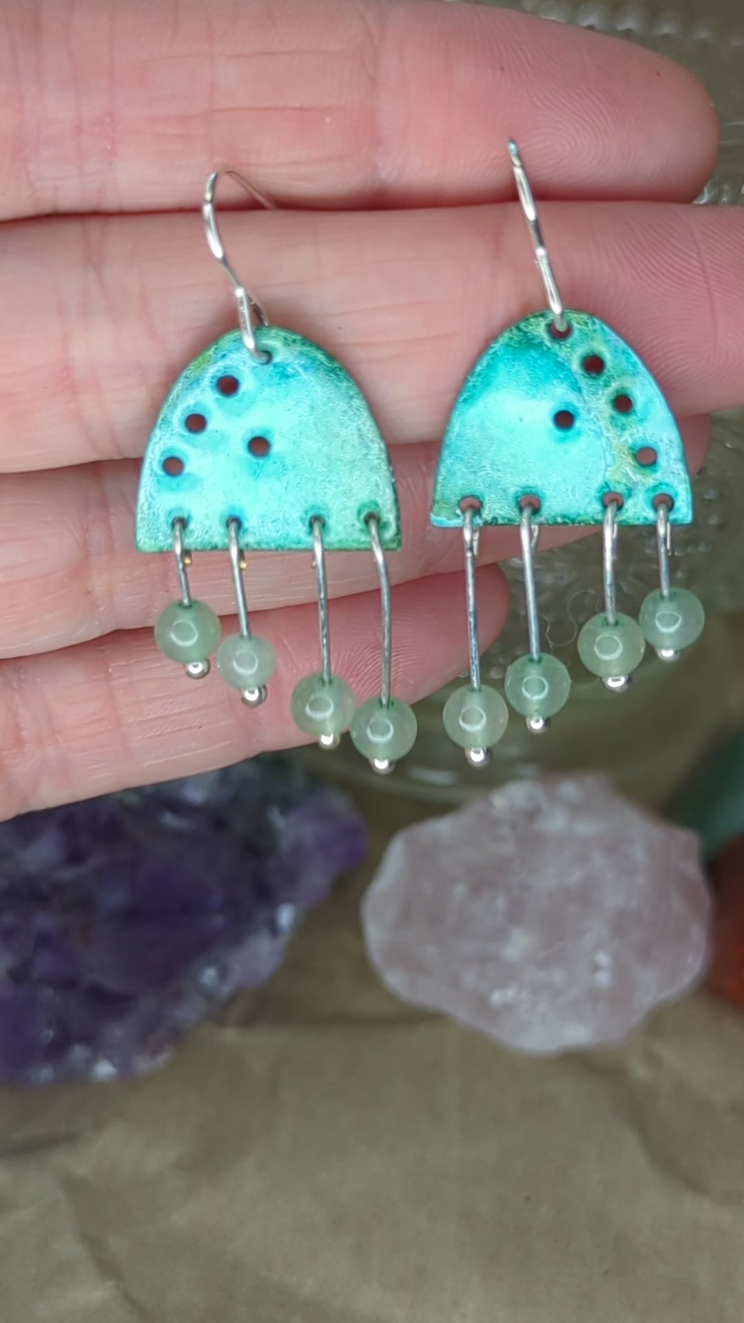 Video of turquoise enamel earrings adorned with green adventurine beads, placed on a hand, the earrings are moving to show all the turquoise colours
