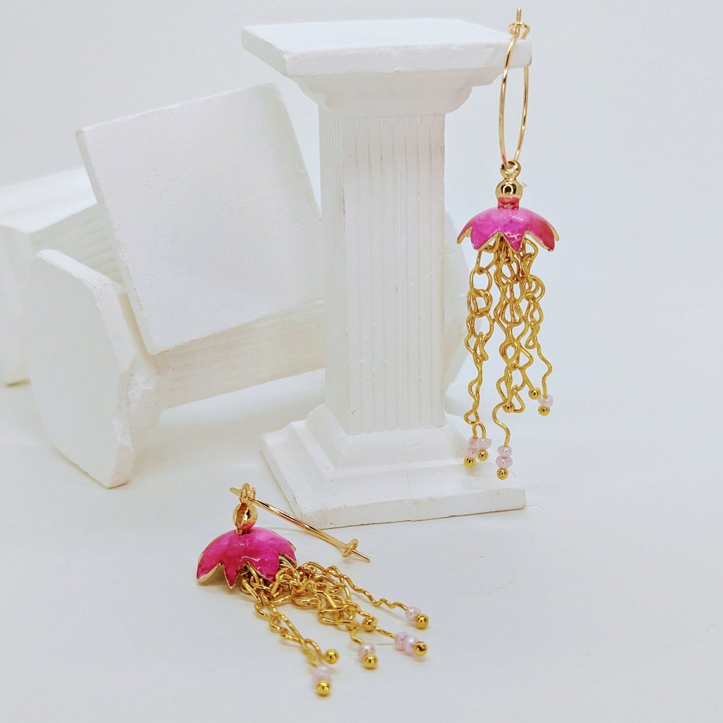 Pink Jelly fish inspired earrings with a cascade of gold plated tentacles with freshwater pearls. Displayed with shells 