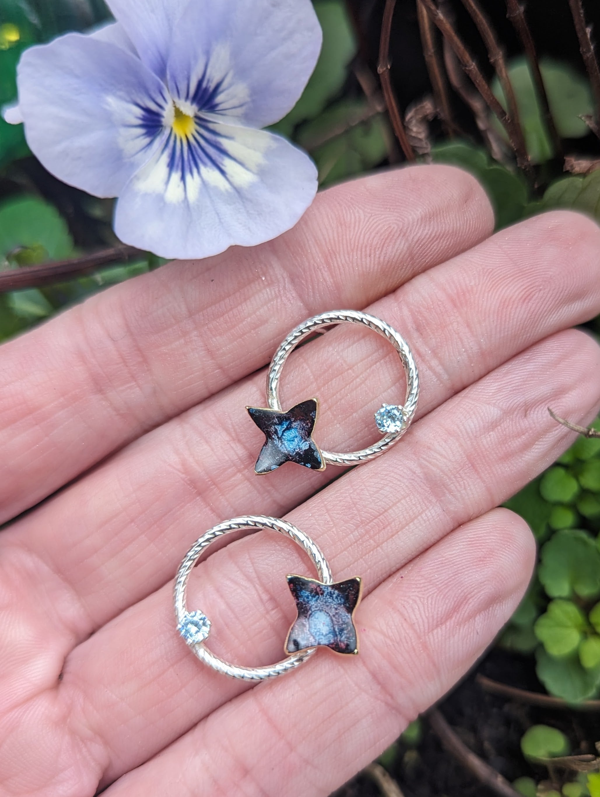 'Theia's Garden' Floral Stud Earrings, Aquamarine Cubic Zirconia. Earrings displayed on models hand
